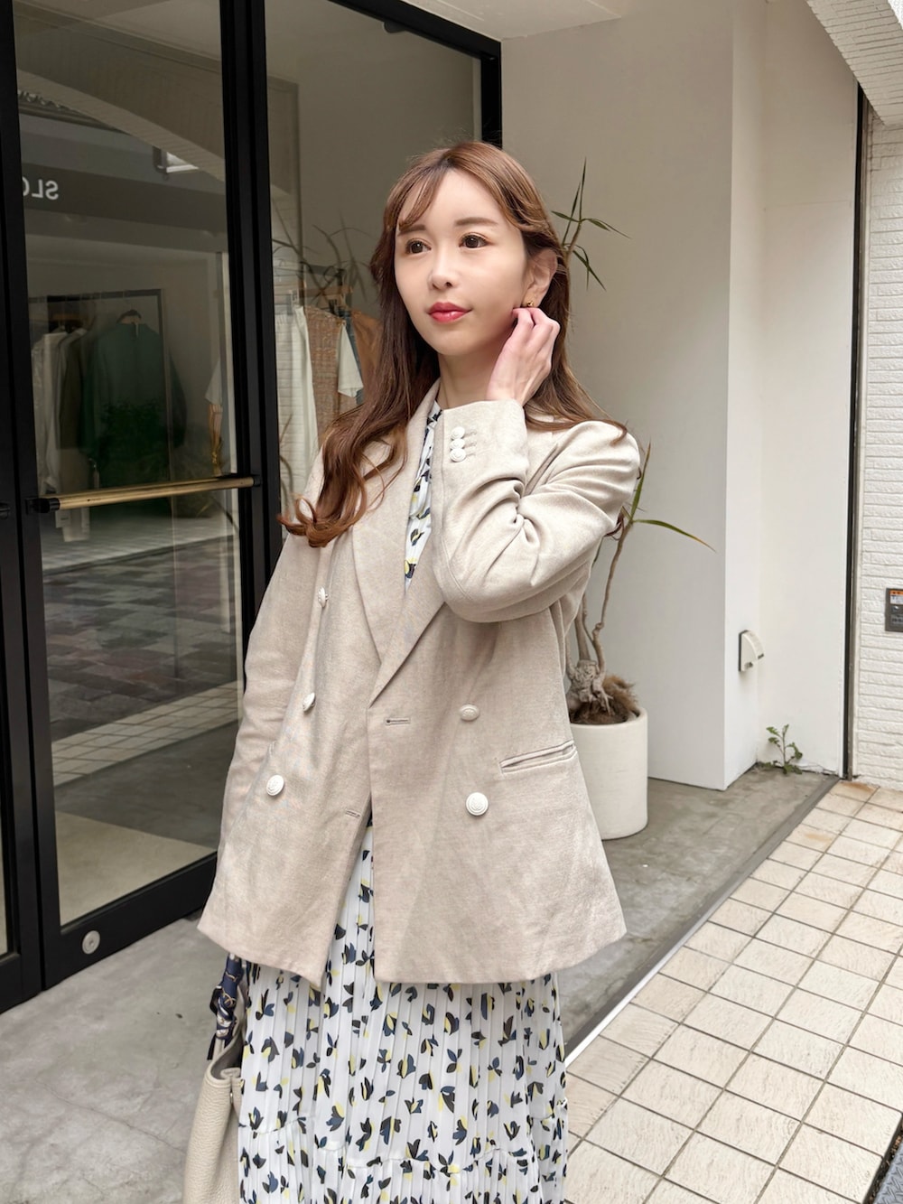 ベージュ系のテーラードジャケット、ホワイト系のワンピース、ブラック系のサンダルを着用したレディースの春コーディネートの2枚目の写真