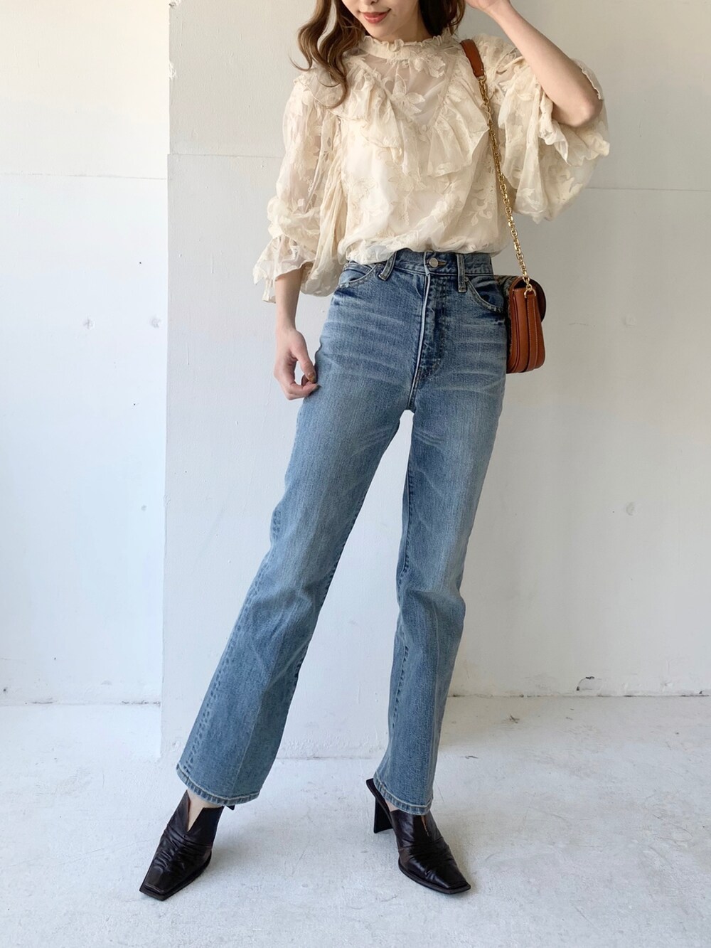 ブルー系のデニムパンツ、ブラウン系のバッグ、ホワイト系のシャツ/ブラウスを着用したレディースの春コーディネートの2枚目の写真