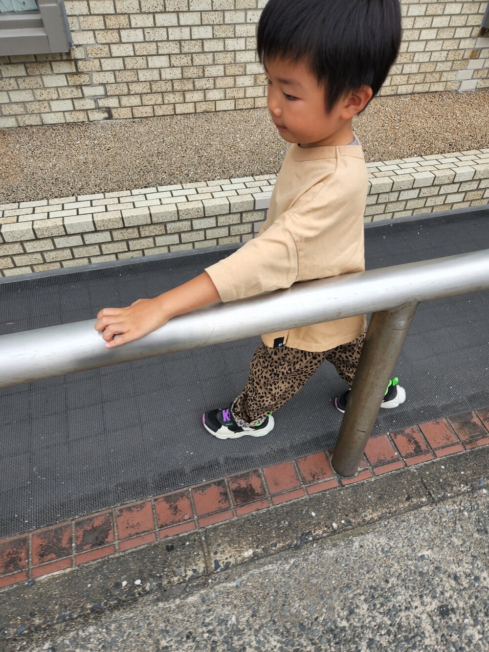 ブラウン系のパンツ、ベージュ系のTシャツ/カットソー、ブラック系のスニーカーを着用したキッズの秋コーディネートの2枚目の写真