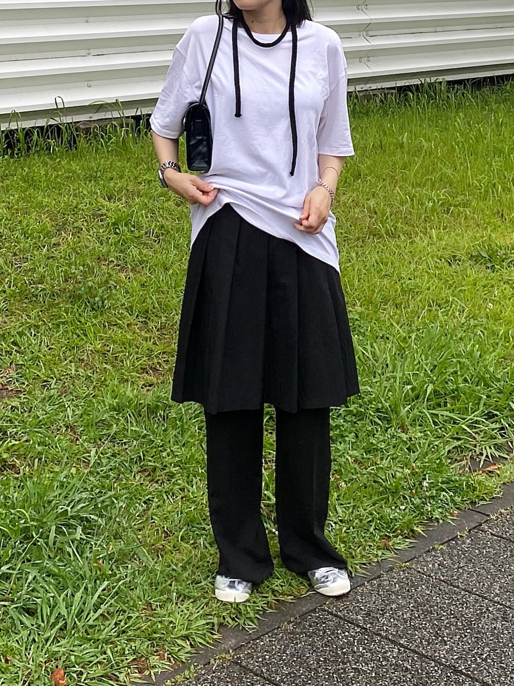 ホワイト系のトップス、ブラック系のバッグ、ブラック系のスカートを着用したレディースの夏コーディネートの2枚目の写真