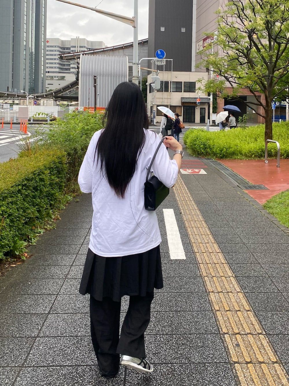 ホワイト系のトップス、ブラック系のバッグ、ブラック系のスカートを着用したレディースの夏コーディネートの4枚目の写真