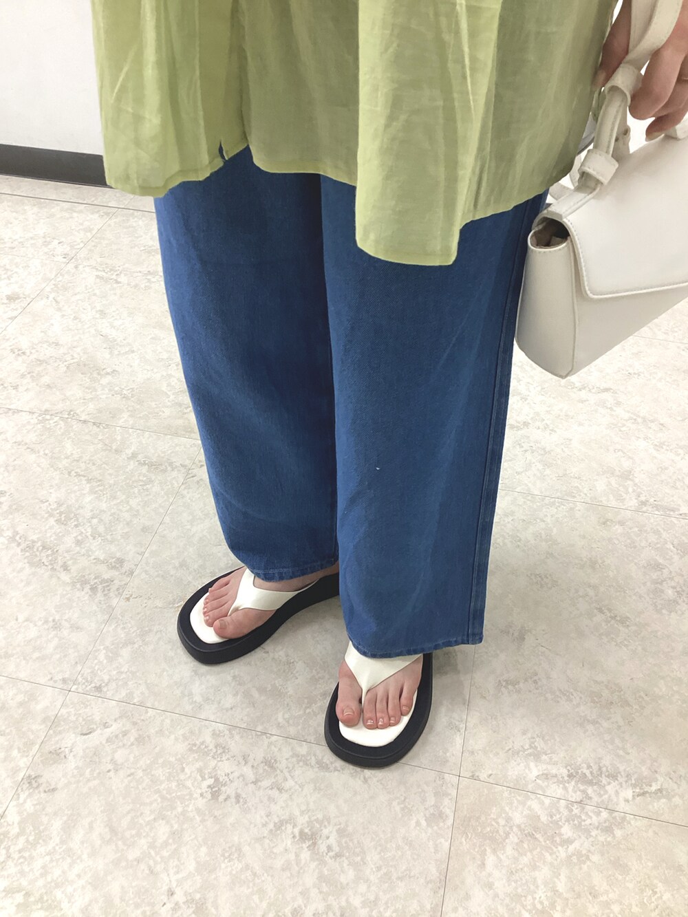 イエロー系のシャツ/ブラウス、ホワイト系のハンドバッグ、ブルー系のデニムパンツを着用したレディースの春コーディネートの3枚目の写真