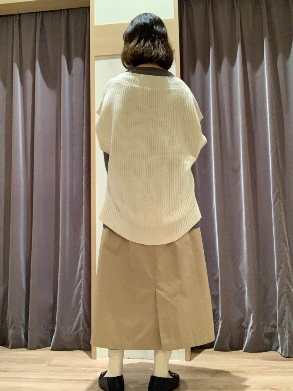 グレー系のTシャツ/カットソー、ホワイト系のベスト、ベージュ系のスカートを着用したレディースの秋コーディネートの3枚目の写真