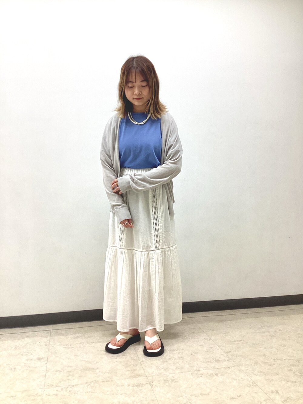 ブルー系のTシャツ/カットソー、グレー系のカーディガン/ボレロ、ホワイト系のスカートを着用したレディースの春コーディネートの2枚目の写真