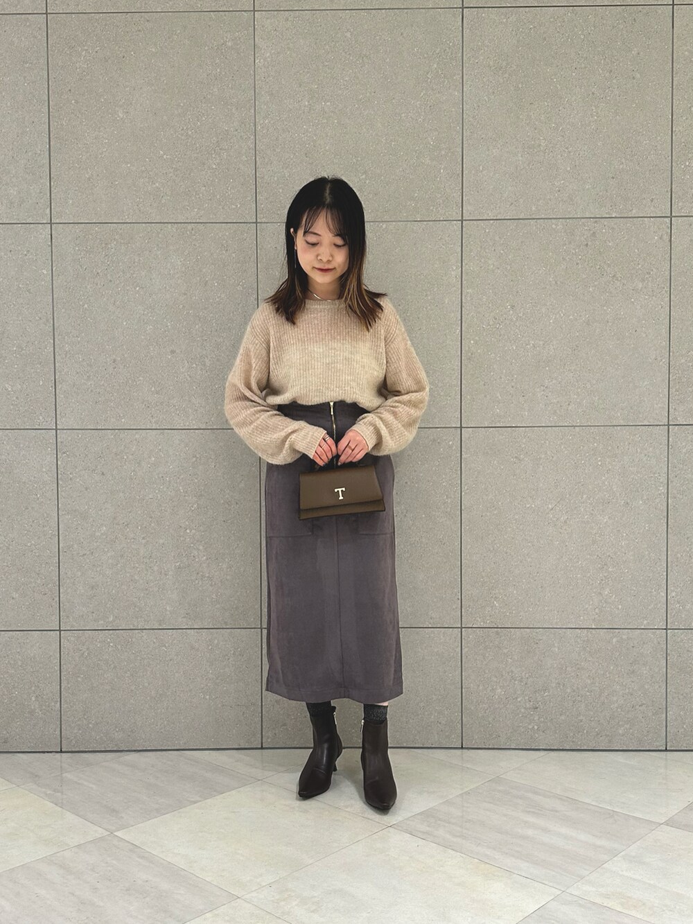 ベージュ系のニット/セーター、グレー系のスカート、ブラウン系のハンドバッグを着用したレディースの秋コーディネートの5枚目の写真