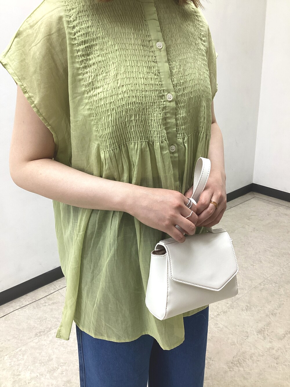 イエロー系のシャツ/ブラウス、ホワイト系のハンドバッグ、ブルー系のデニムパンツを着用したレディースの春コーディネートの4枚目の写真