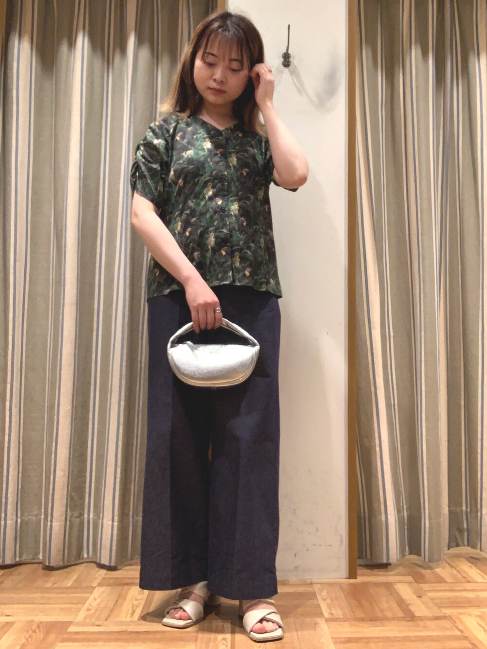 グリーン系のシャツ/ブラウス、シルバー系のハンドバッグ、ブルー系のデニムパンツを着用したレディースの春コーディネートの2枚目の写真