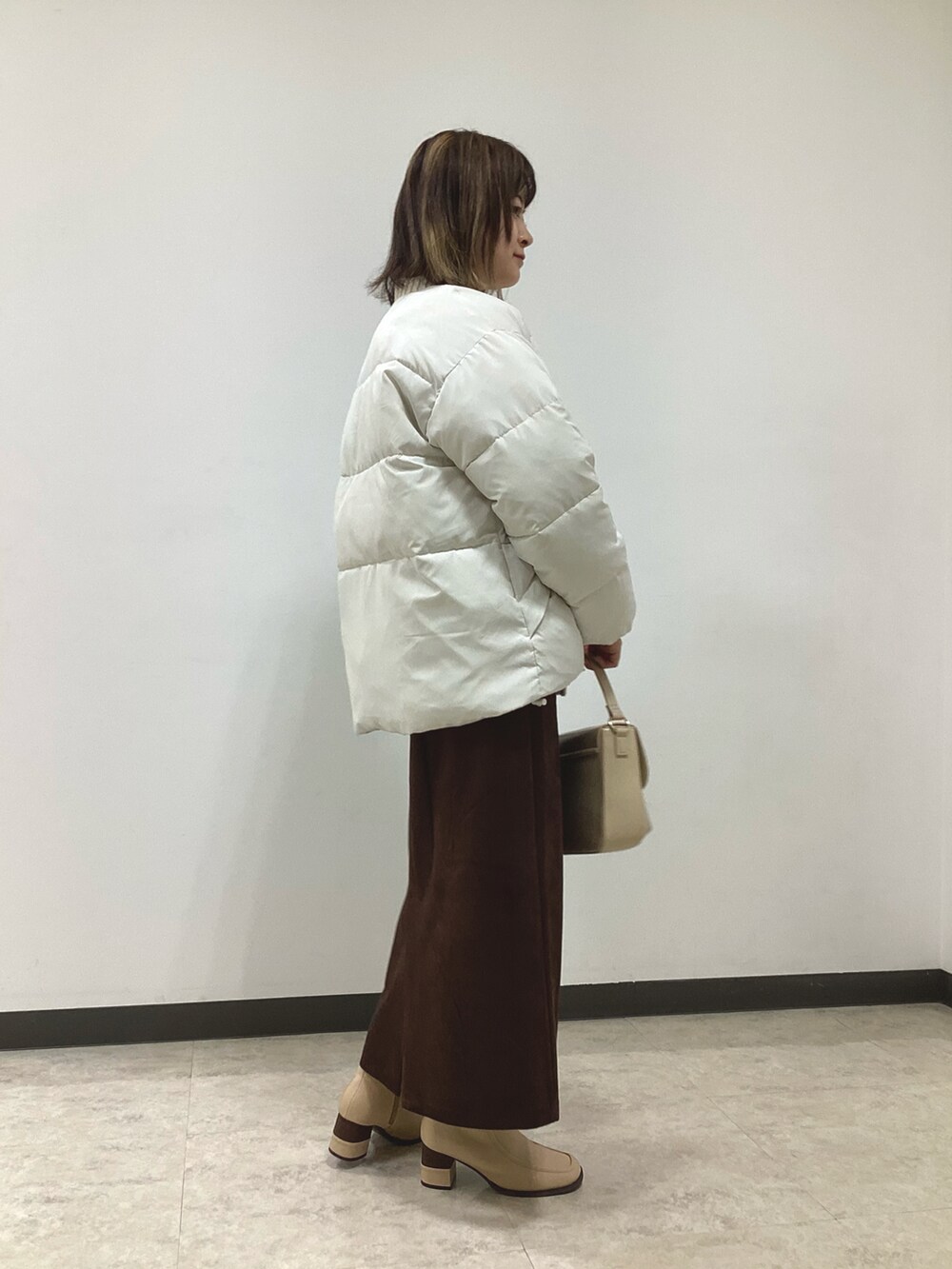 ホワイト系のニット/セーター、ホワイト系のその他アウター、ブラウン系のスカートを着用したレディースの冬コーディネートの5枚目の写真