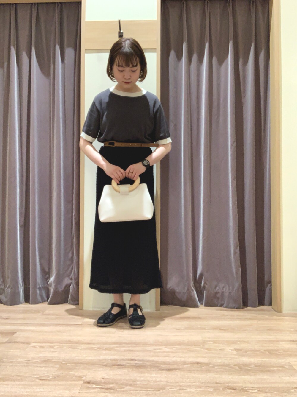 グレー系のニット/セーター、ブラック系のスカート、ホワイト系のトートバッグを着用したレディースの春コーディネートの2枚目の写真