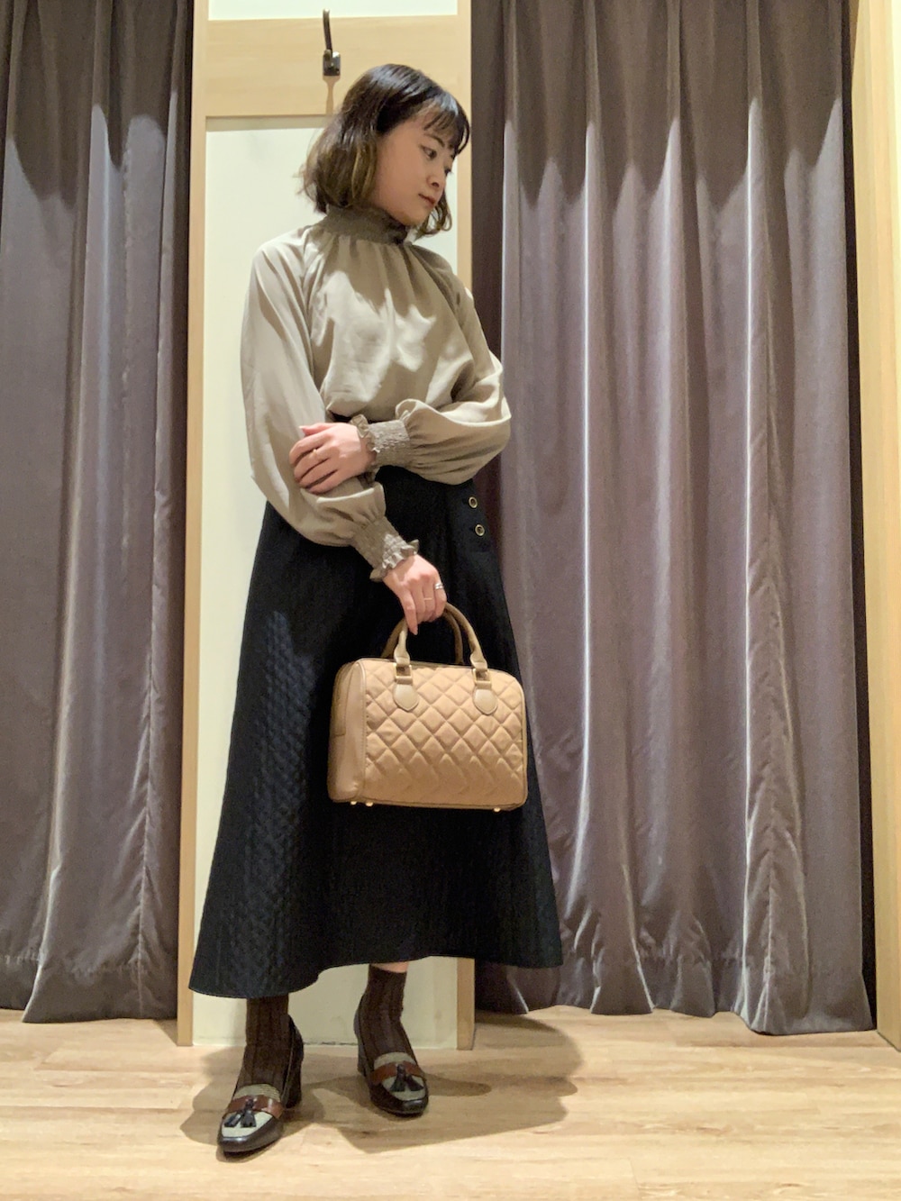 ブラウン系のシャツ/ブラウス、ブラック系のスカート、ベージュ系のハンドバッグを着用したレディースの秋コーディネートの2枚目の写真