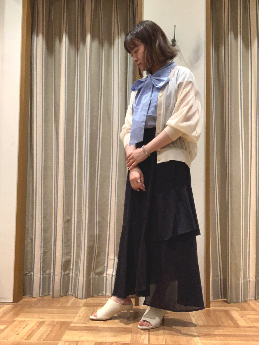 ブルー系のシャツ/ブラウス、ホワイト系のカーディガン/ボレロ、ブラック系のスカートを着用したレディースの夏コーディネートの2枚目の写真