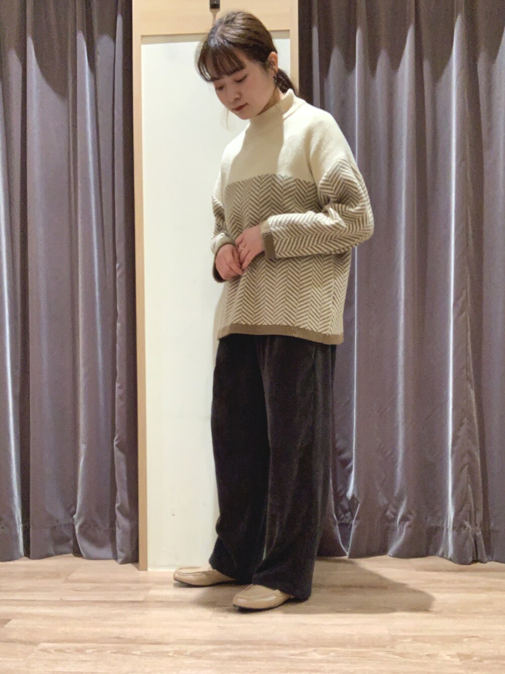 グリーン系のノーカラーコート、ベージュ系のニット/セーター、グレー系のその他パンツを着用したレディースの冬コーディネートの2枚目の写真