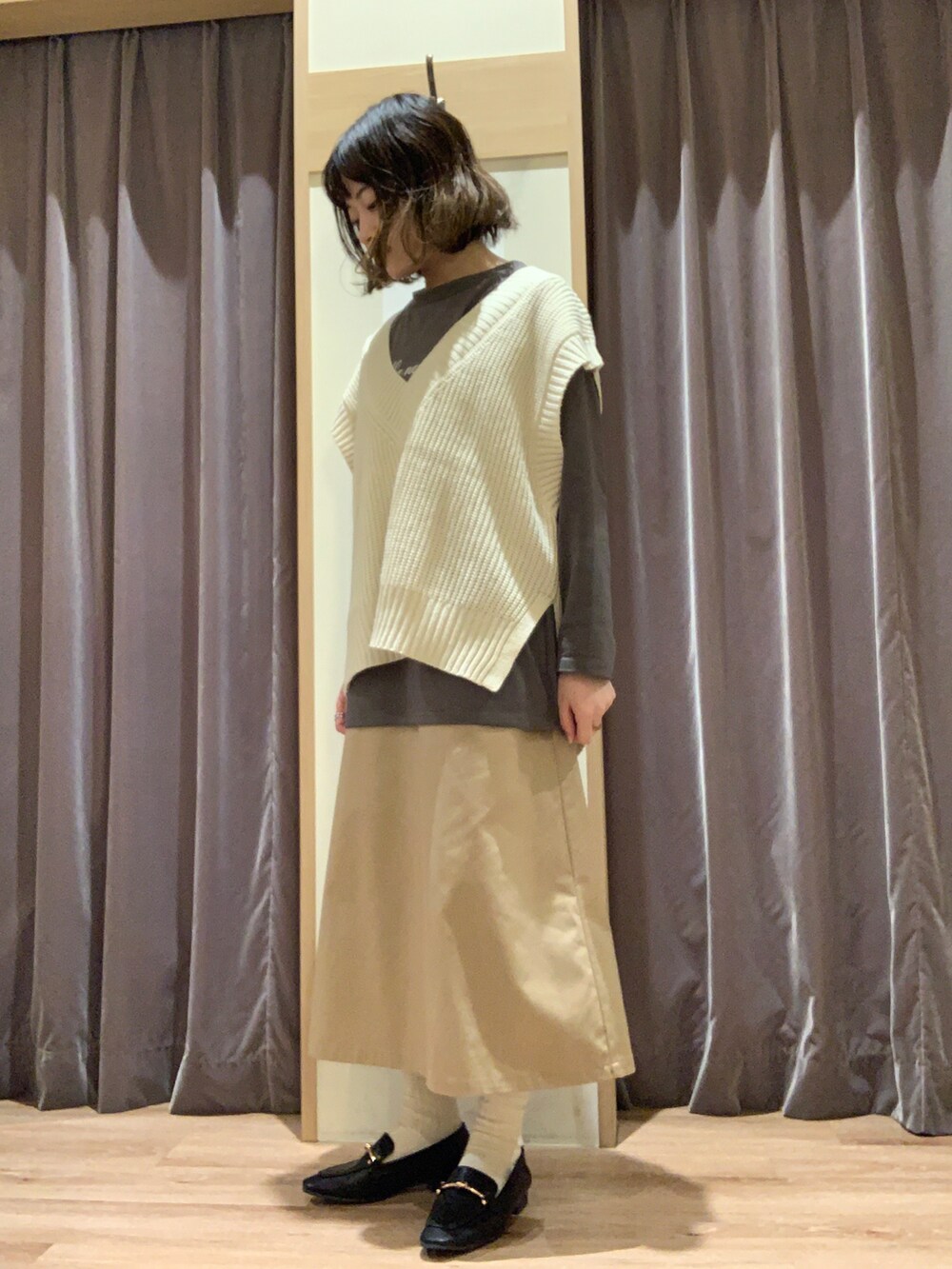 グレー系のTシャツ/カットソー、ホワイト系のベスト、ベージュ系のスカートを着用したレディースの秋コーディネートの4枚目の写真