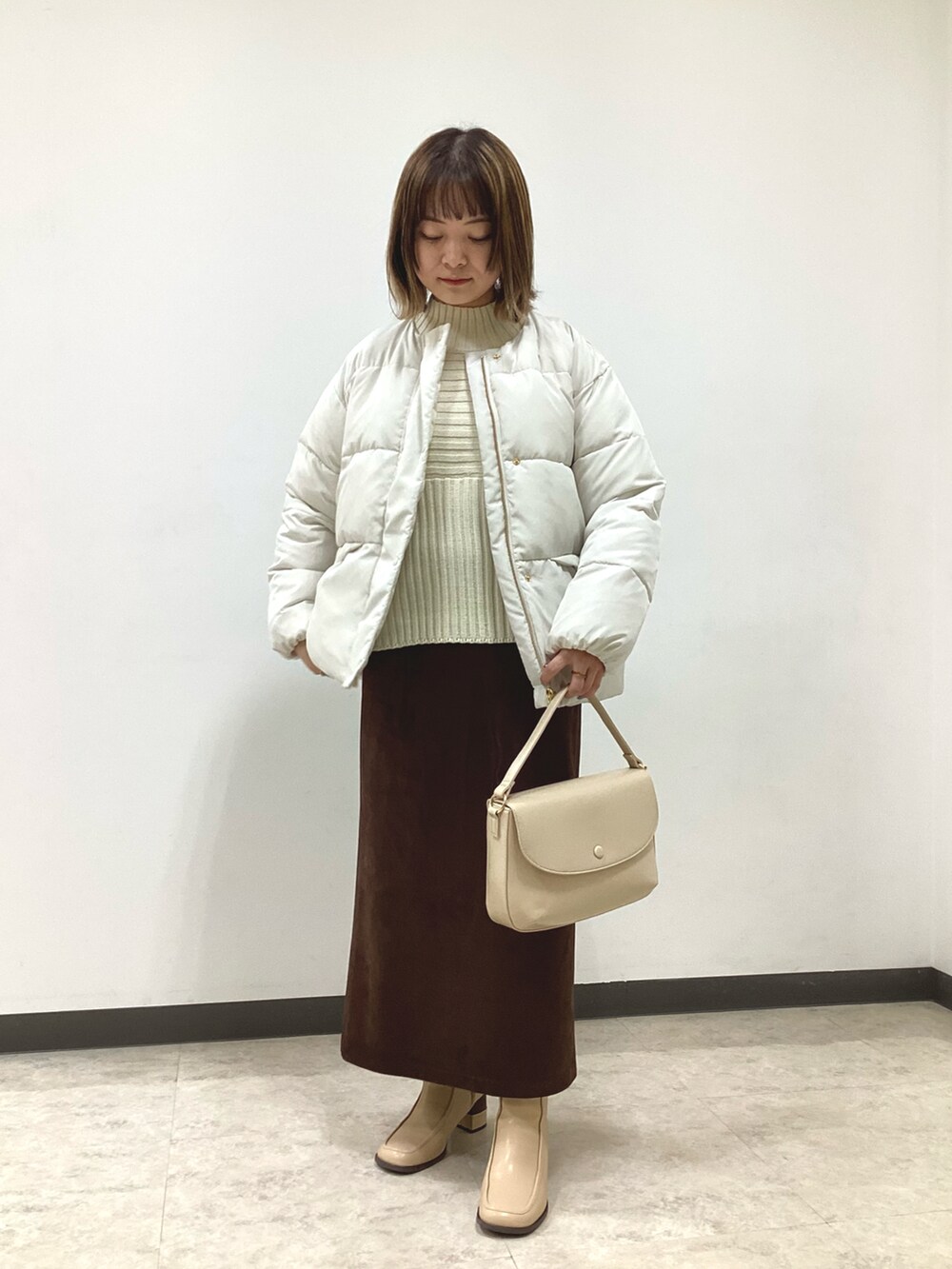 ホワイト系のニット/セーター、ホワイト系のその他アウター、ブラウン系のスカートを着用したレディースの冬コーディネートの4枚目の写真