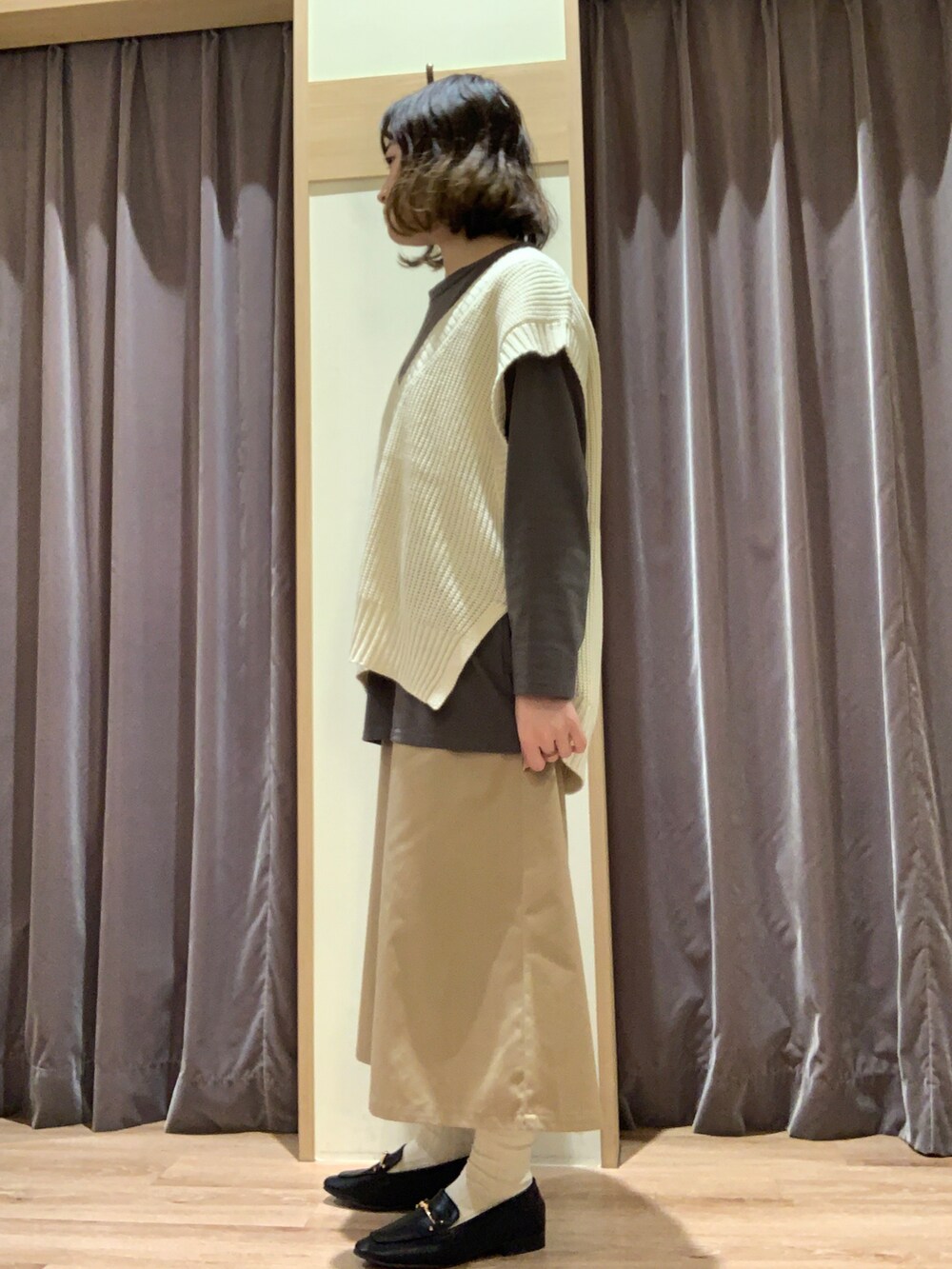 グレー系のTシャツ/カットソー、ホワイト系のベスト、ベージュ系のスカートを着用したレディースの秋コーディネートの2枚目の写真