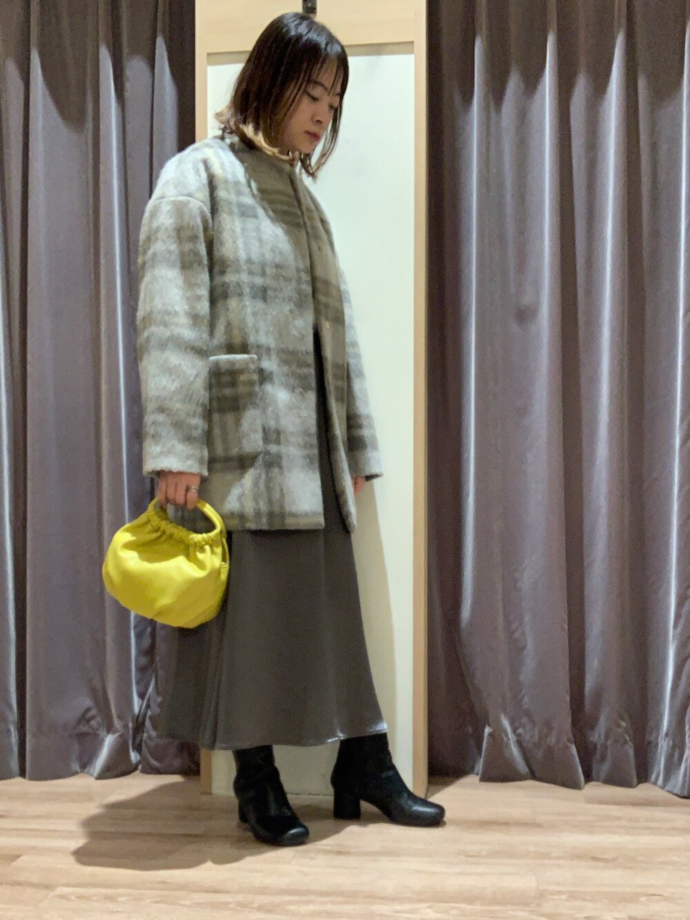 ベージュ系のニット/セーター、グレー系のノーカラーコート、イエロー系のハンドバッグを着用したレディースの秋コーディネートの2枚目の写真