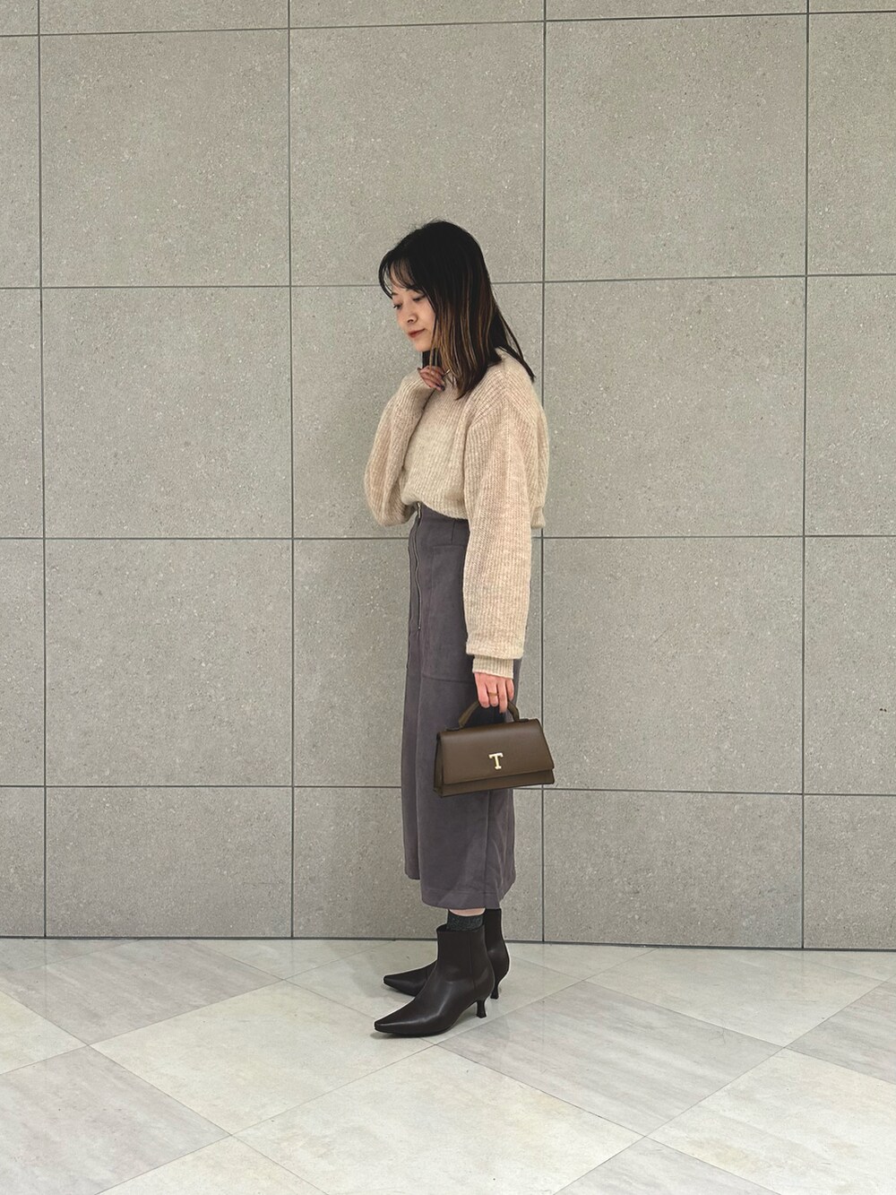 ベージュ系のニット/セーター、グレー系のスカート、ブラウン系のハンドバッグを着用したレディースの秋コーディネートの3枚目の写真