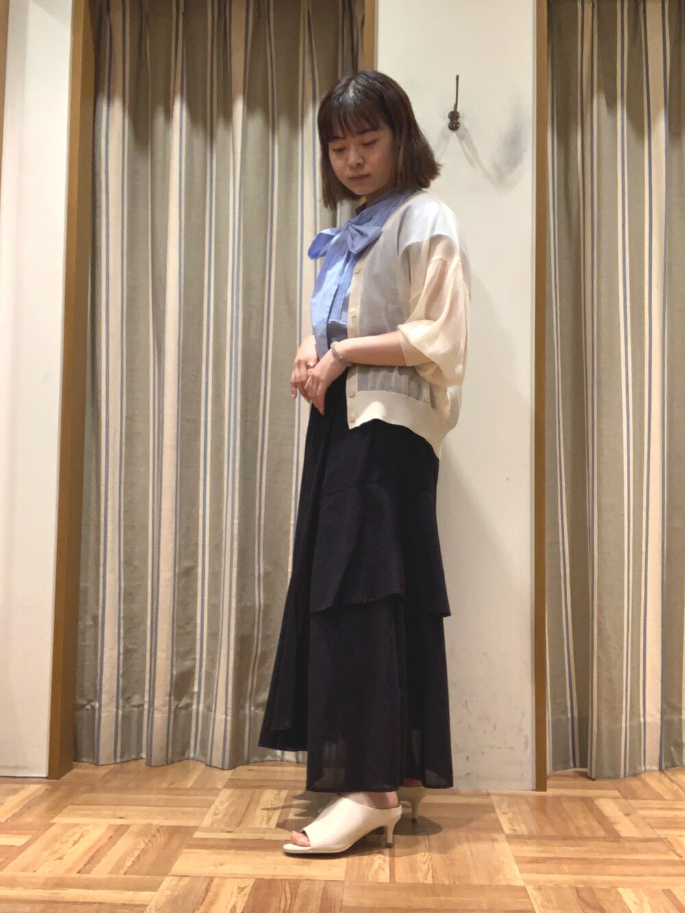 ブルー系のシャツ/ブラウス、ホワイト系のカーディガン/ボレロ、ブラック系のスカートを着用したレディースの夏コーディネートの4枚目の写真