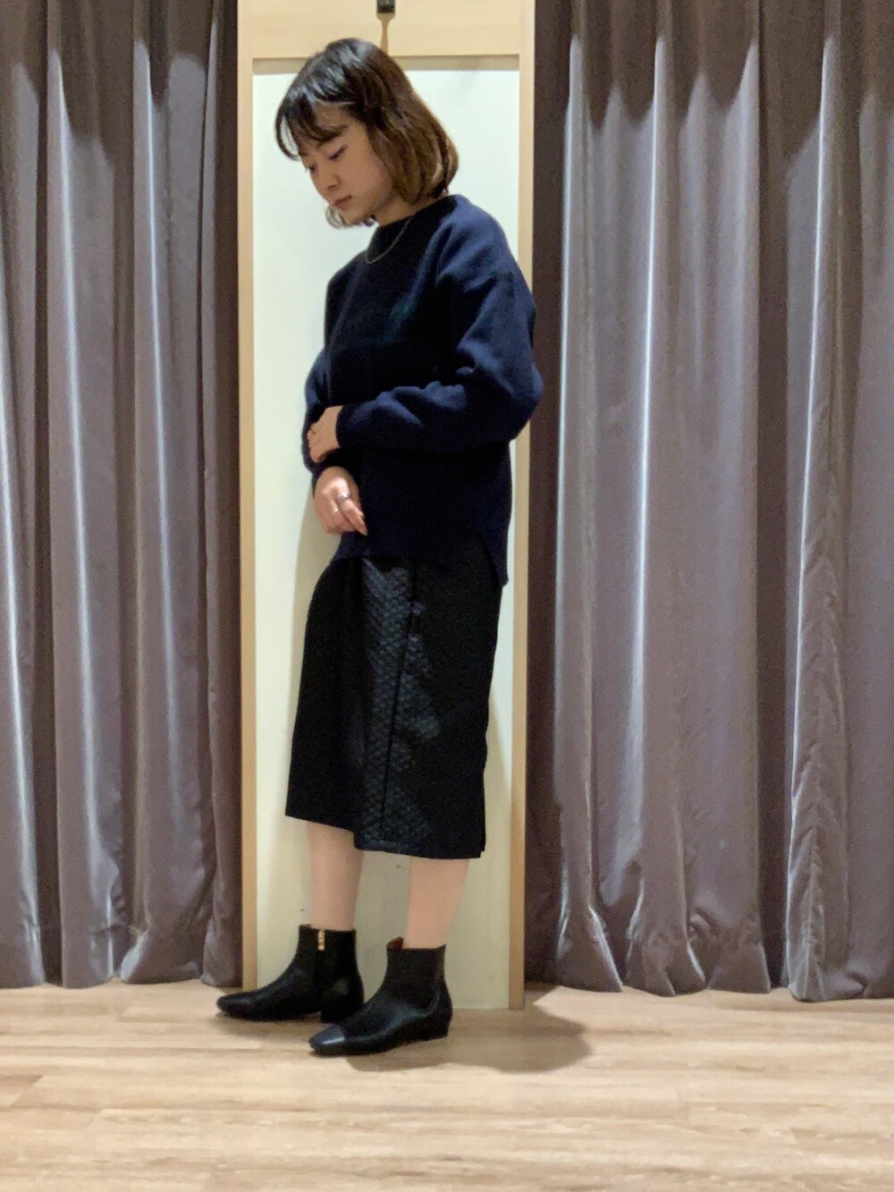 ブルー系のニット/セーター、ブラック系のスカート、ブラック系のブーツを着用したレディースの秋コーディネートの2枚目の写真