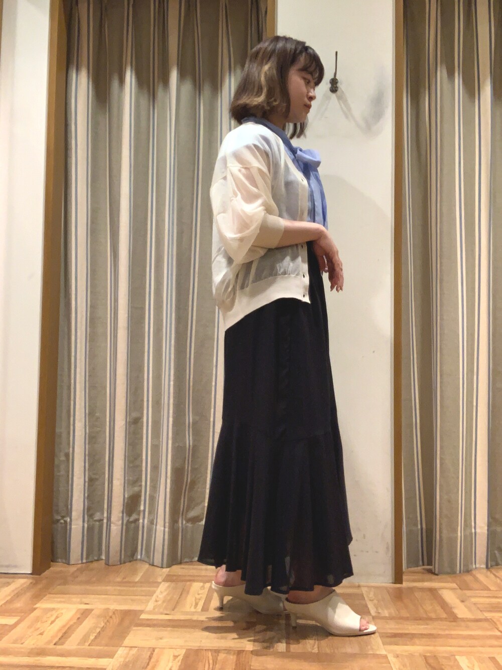 ブルー系のシャツ/ブラウス、ホワイト系のカーディガン/ボレロ、ブラック系のスカートを着用したレディースの夏コーディネートの3枚目の写真