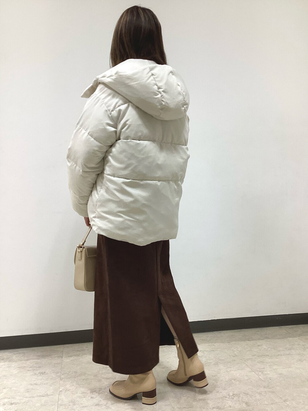 ホワイト系のニット/セーター、ホワイト系のその他アウター、ブラウン系のスカートを着用したレディースの冬コーディネートの2枚目の写真