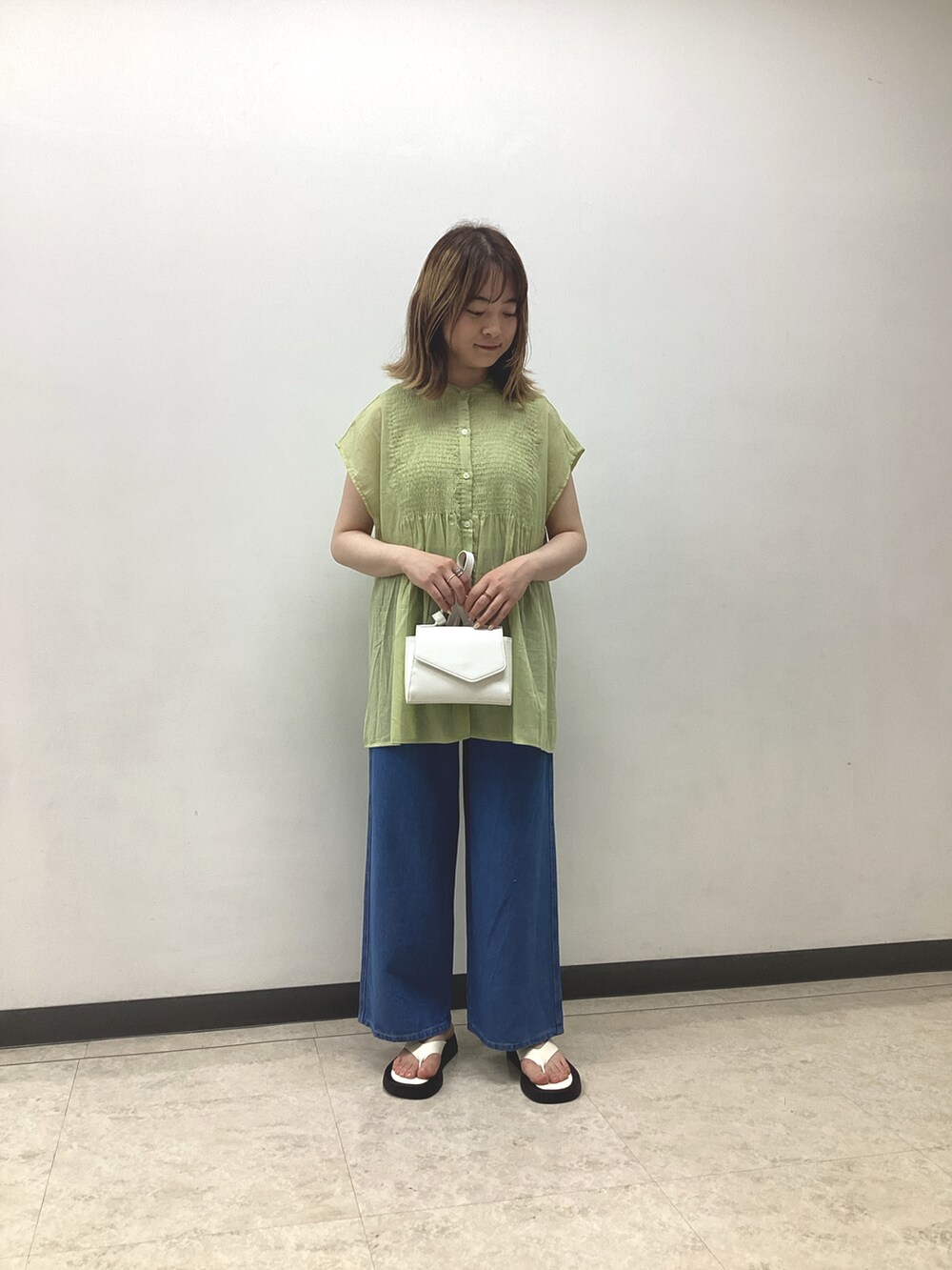 イエロー系のシャツ/ブラウス、ホワイト系のハンドバッグ、ブルー系のデニムパンツを着用したレディースの春コーディネートの2枚目の写真