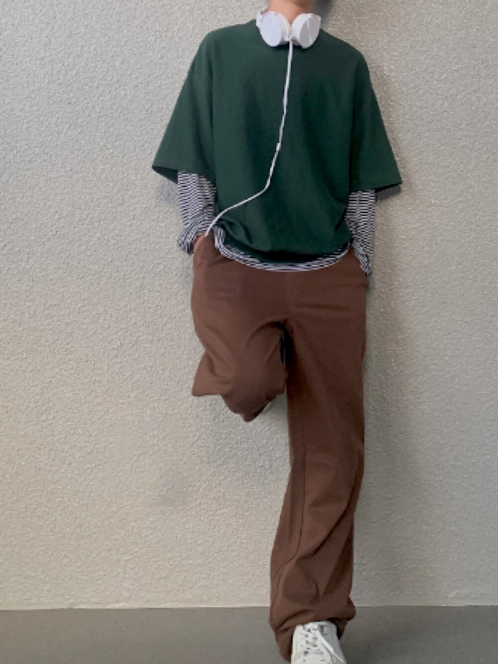 グリーン系のトップス、ブラウン系のパンツ、ホワイト系のスニーカーを着用したメンズの春コーディネートの2枚目の写真