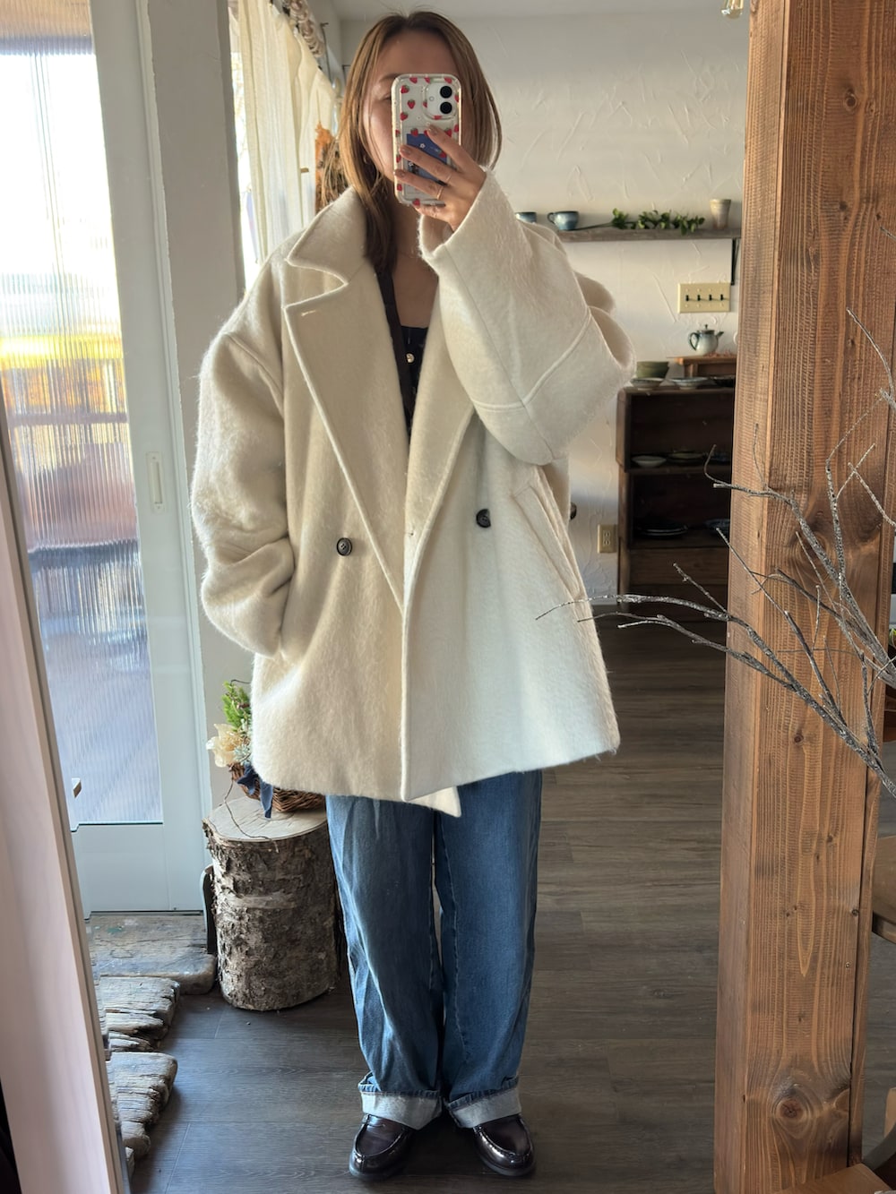 ブラウン系のテーラードジャケット、ブラック系のニット/セーター、ホワイト系のハンドバッグを着用したレディースの秋コーディネートの2枚目の写真