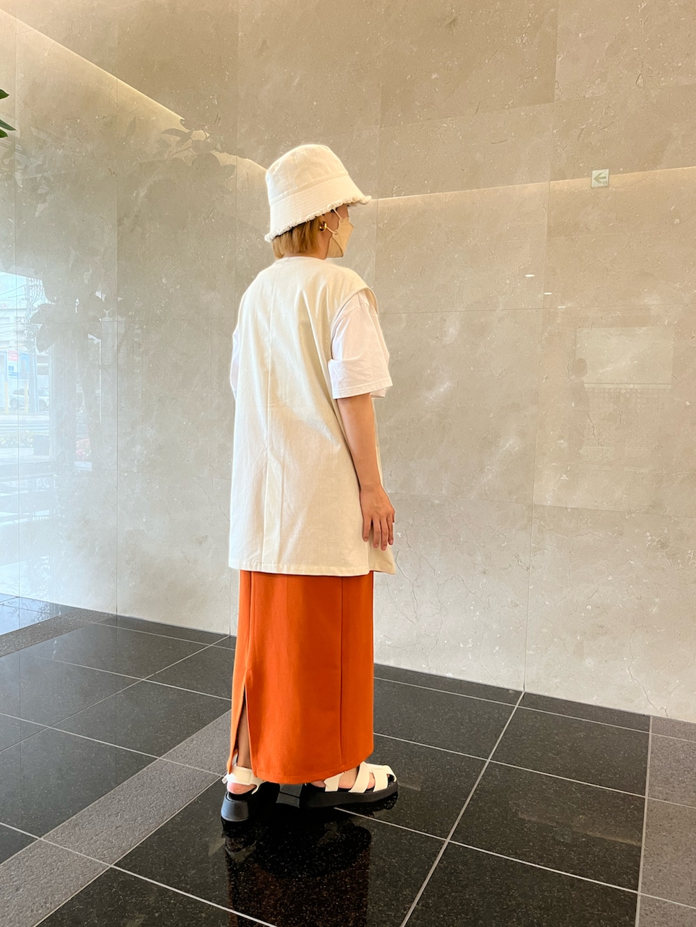 ホワイト系のTシャツ/カットソー、ベージュ系のベスト、オレンジ系のスカートを着用したレディースの春コーディネートの2枚目の写真