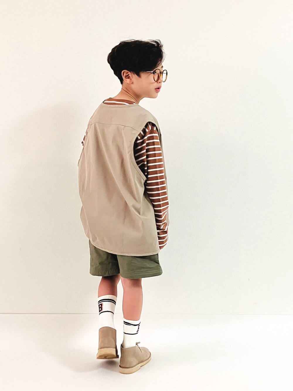 ベージュ系のTシャツ/カットソー、グリーン系のパンツ、ベージュ系のベストを着用したキッズの秋コーディネートの3枚目の写真