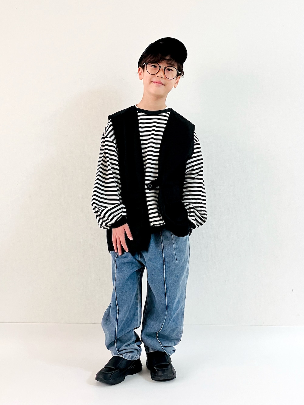 ブラック系のTシャツ/カットソー、ブラック系のベスト、ブラック系のスニーカーを着用したキッズの秋コーディネートの2枚目の写真