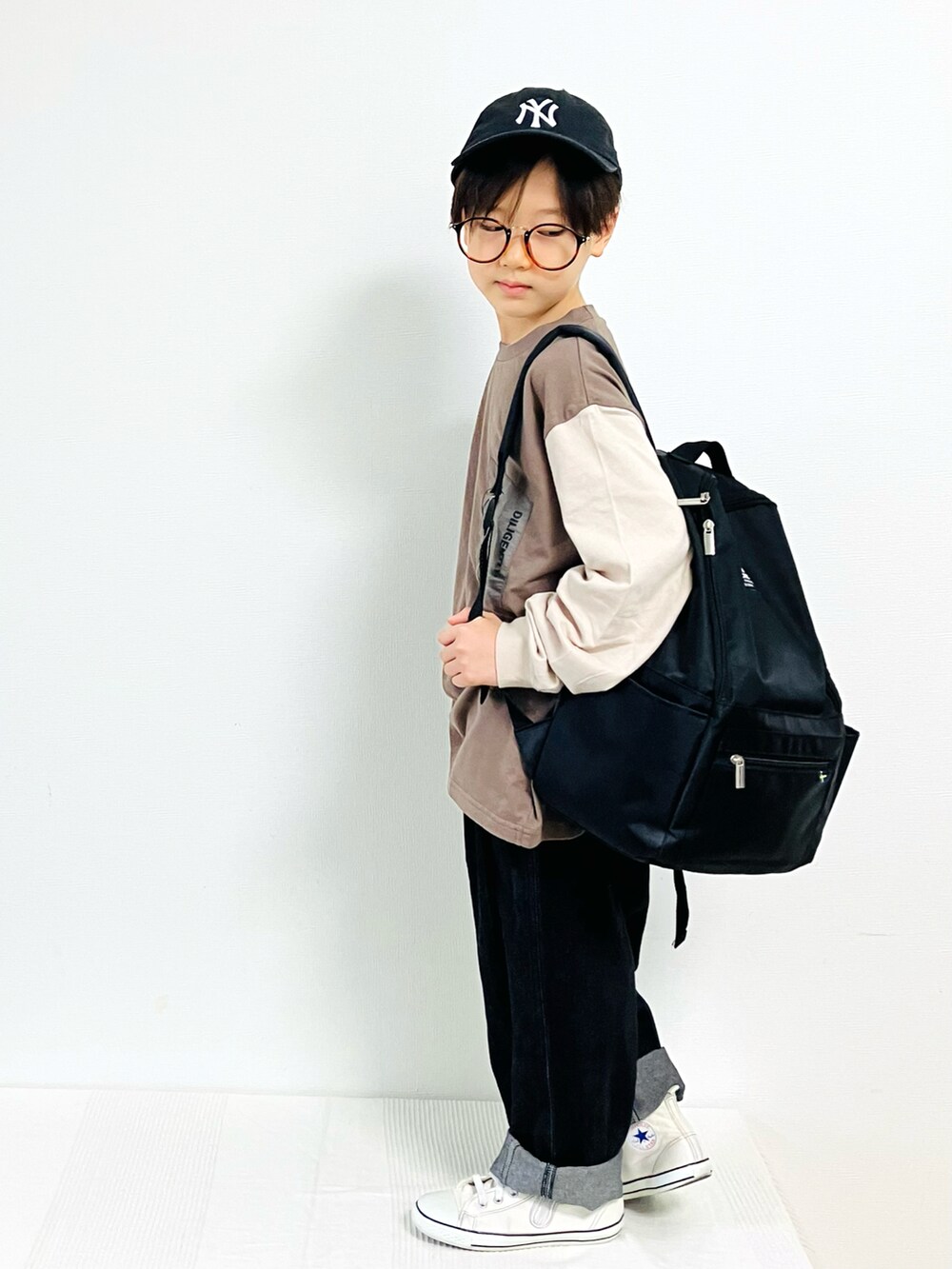 ブラウン系のTシャツ/カットソー、ブラック系のデニムパンツ、ホワイト系のスニーカーを着用したキッズの秋コーディネートの2枚目の写真