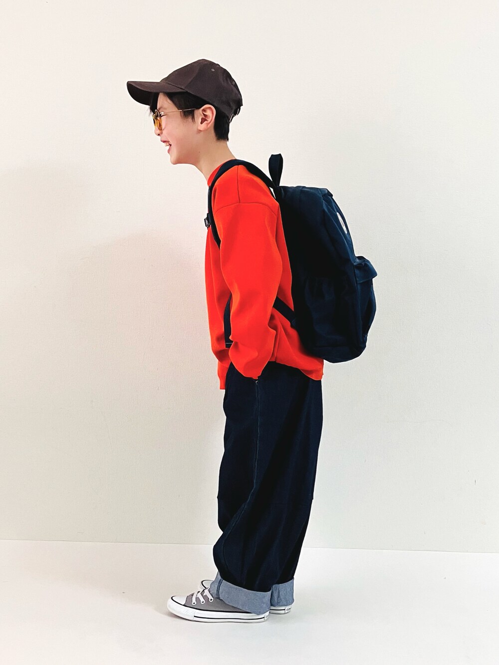 オレンジ系のニット/セーター、ブルー系のその他パンツ、グレー系のスニーカーを着用したキッズの春コーディネートの3枚目の写真