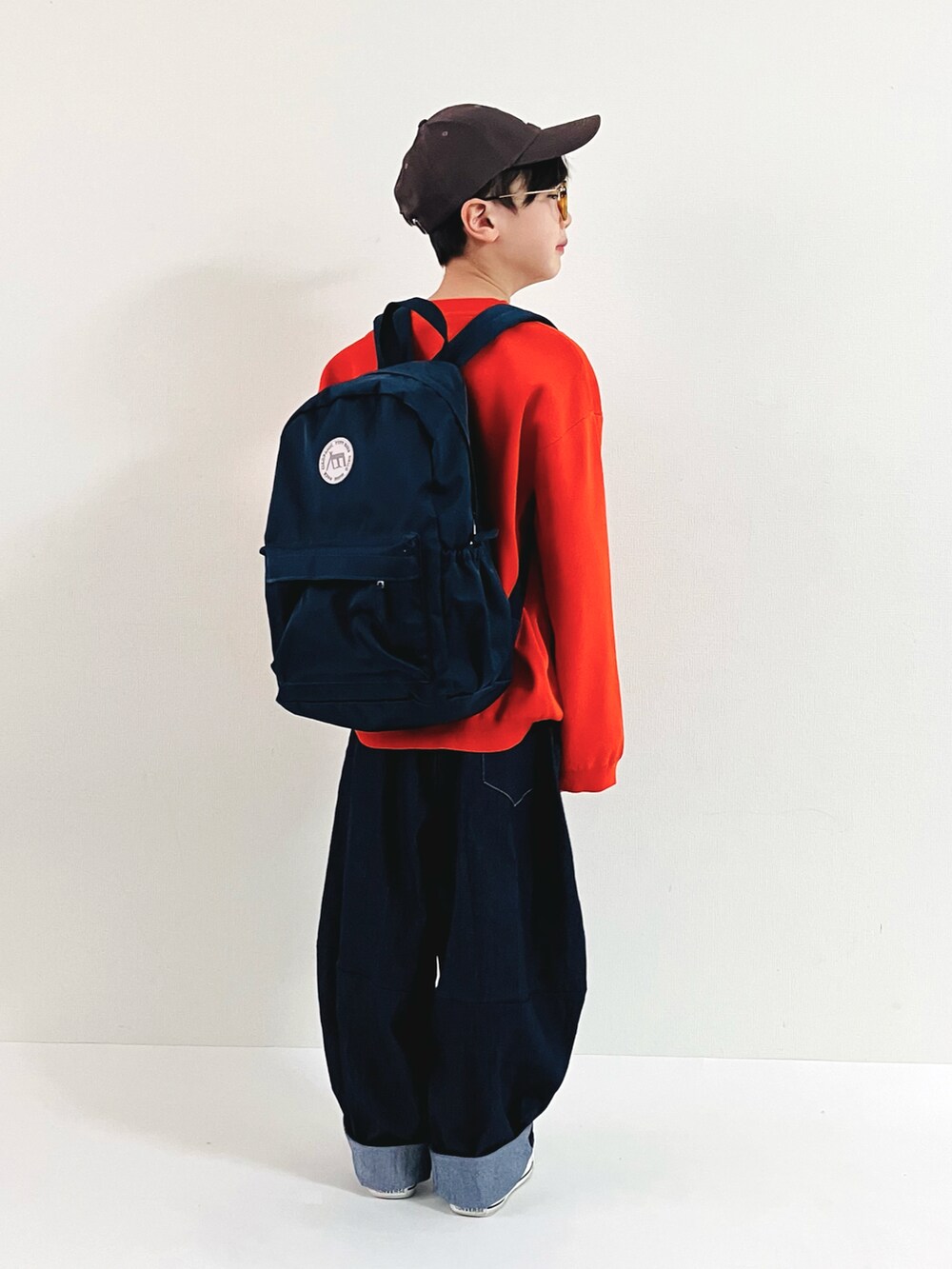 オレンジ系のニット/セーター、ブルー系のその他パンツ、グレー系のスニーカーを着用したキッズの春コーディネートの2枚目の写真