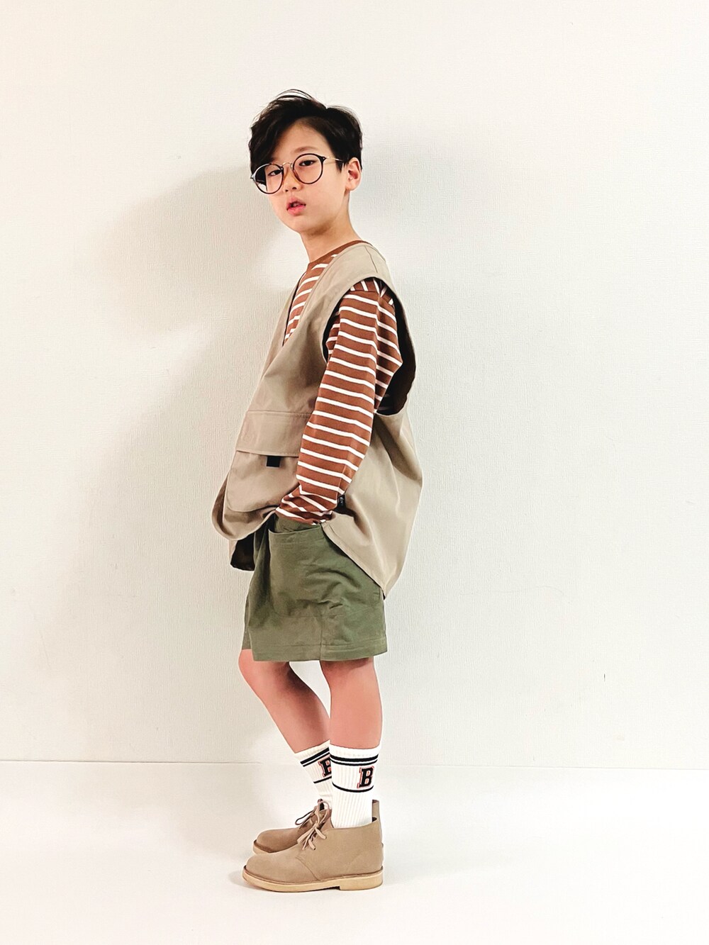 ベージュ系のTシャツ/カットソー、グリーン系のパンツ、ベージュ系のベストを着用したキッズの秋コーディネートの2枚目の写真