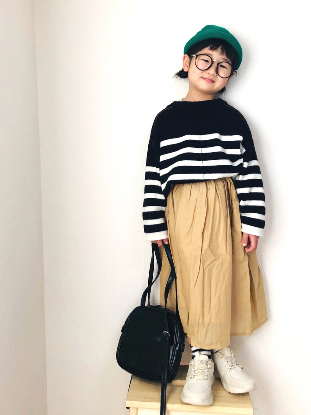 ホワイト系のニット/セーター、ベージュ系のスカート、ベージュ系のスニーカーを着用したキッズの冬コーディネートの2枚目の写真