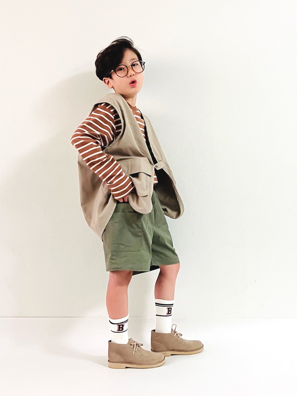 ベージュ系のTシャツ/カットソー、グリーン系のパンツ、ベージュ系のベストを着用したキッズの秋コーディネートの4枚目の写真