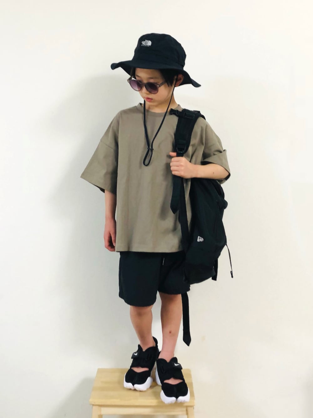 ブラック系のパンツ、グリーン系のTシャツ/カットソー、ブラック系のバックパック/リュックを着用したキッズの春コーディネートの2枚目の写真