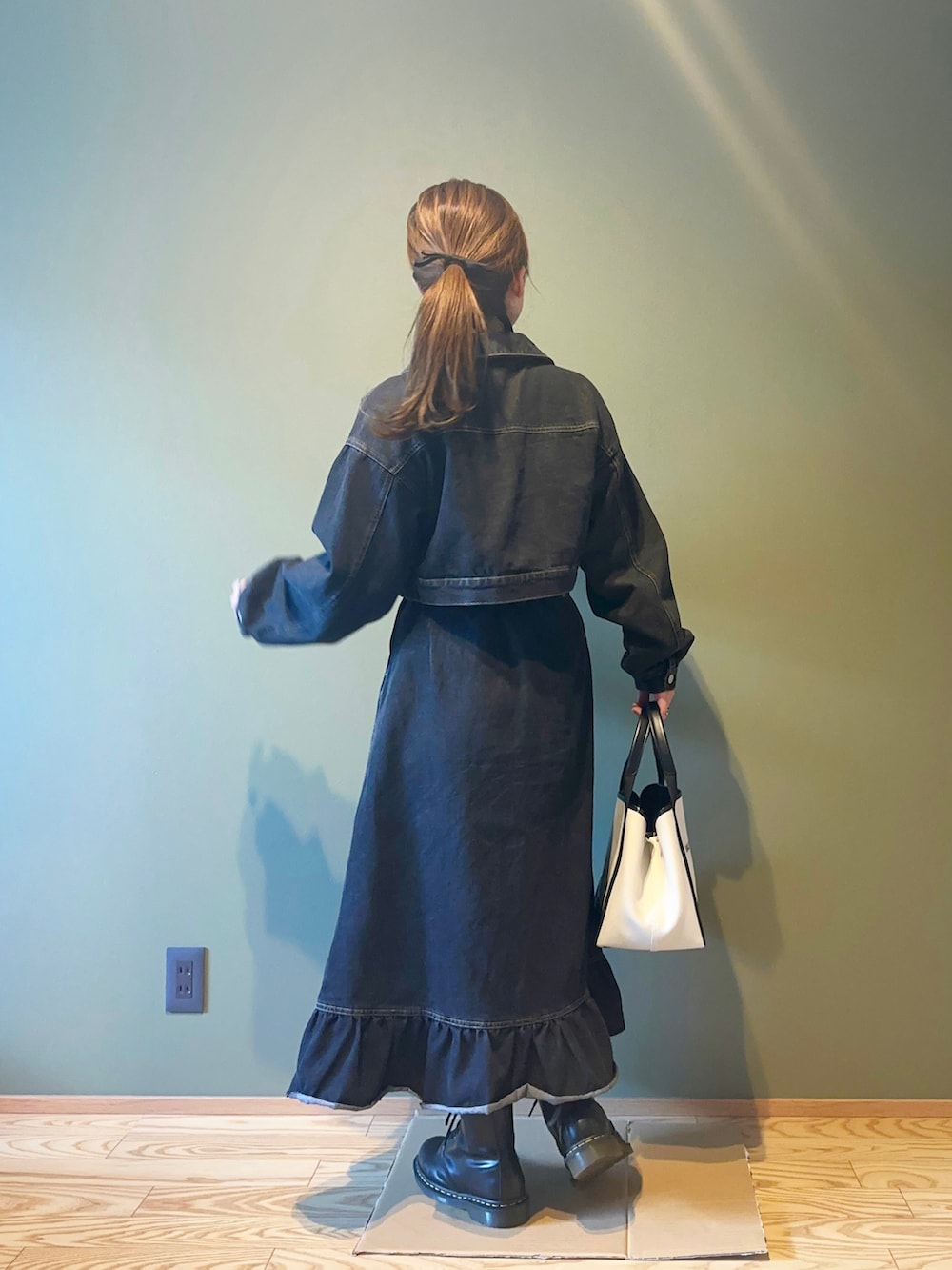 ブラック系のワンピース、ブラック系のブーツ、ホワイト系のトートバッグを着用したレディースの秋コーディネートの2枚目の写真