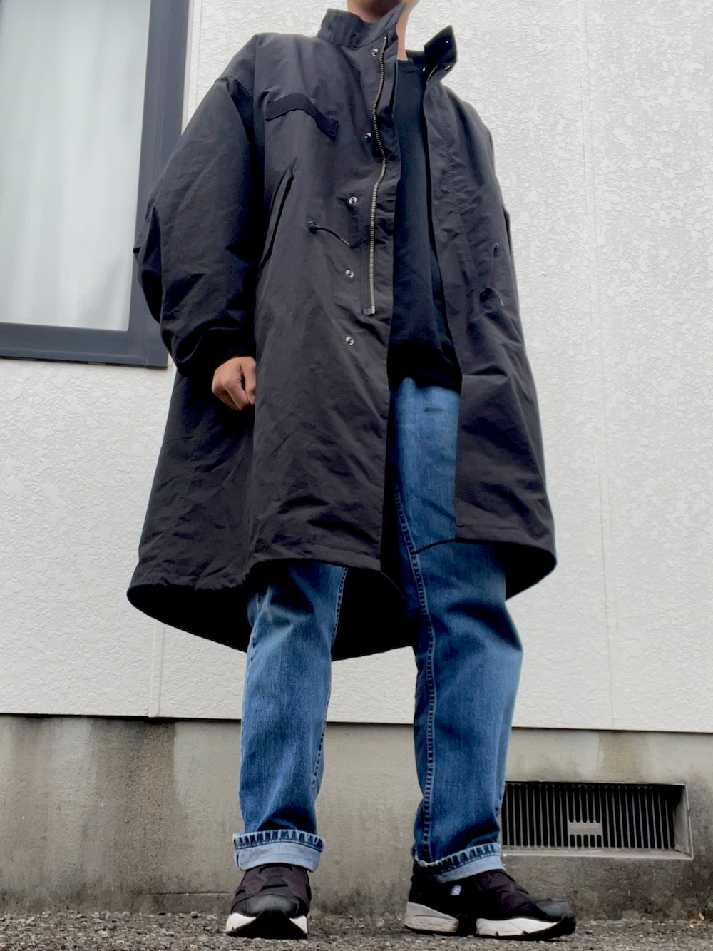 ブラック系のモッズコート、ブルー系のデニムパンツ、ブラック系のスニーカーを着用したメンズの冬コーディネートの3枚目の写真
