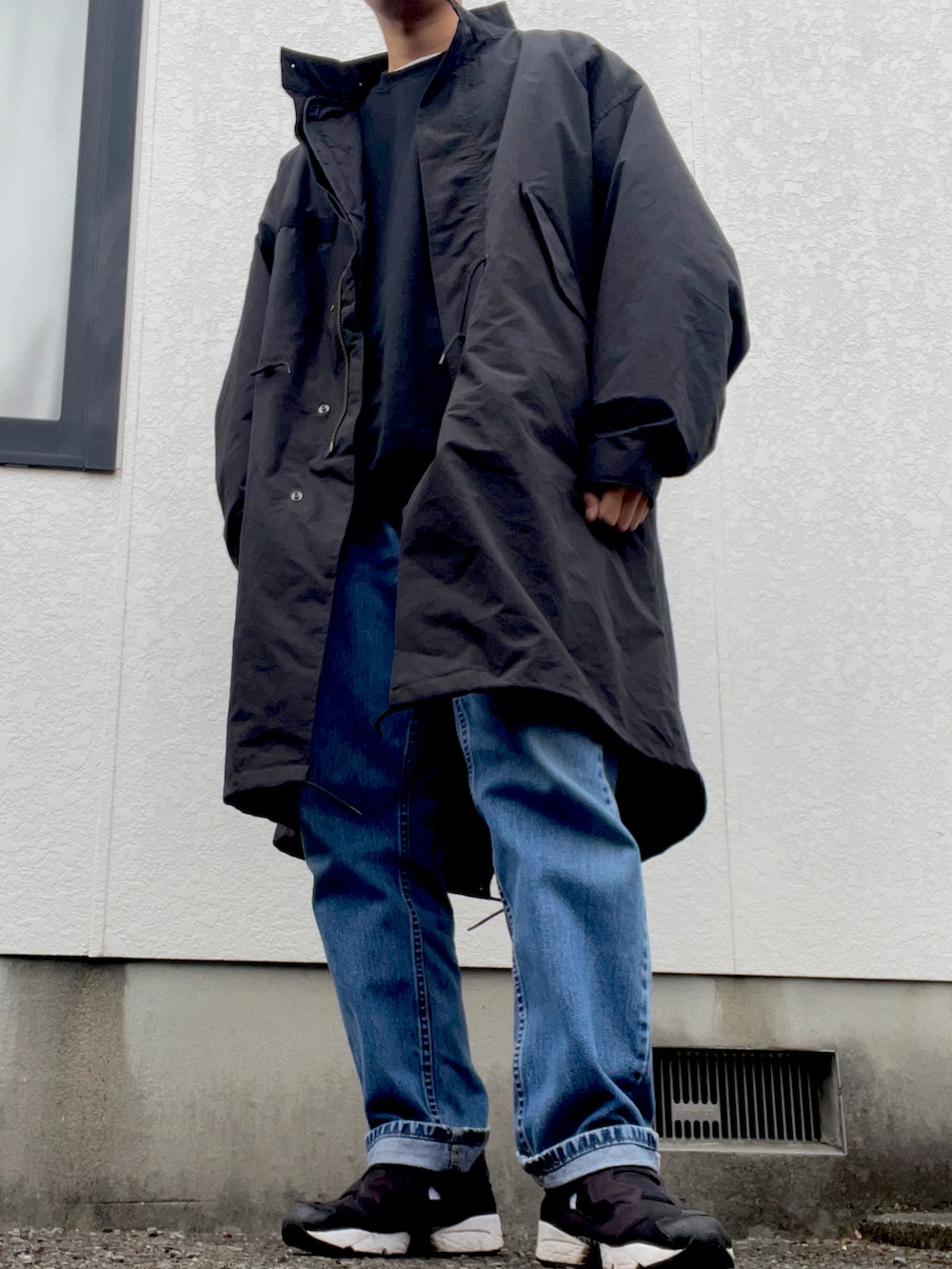 ブラック系のモッズコート、ブルー系のデニムパンツ、ブラック系のスニーカーを着用したメンズの冬コーディネートの2枚目の写真