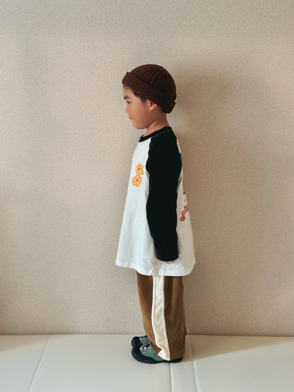 ホワイト系のTシャツ/カットソー、ベージュ系のパンツ、グリーン系のスニーカーを着用したキッズの春コーディネートの3枚目の写真