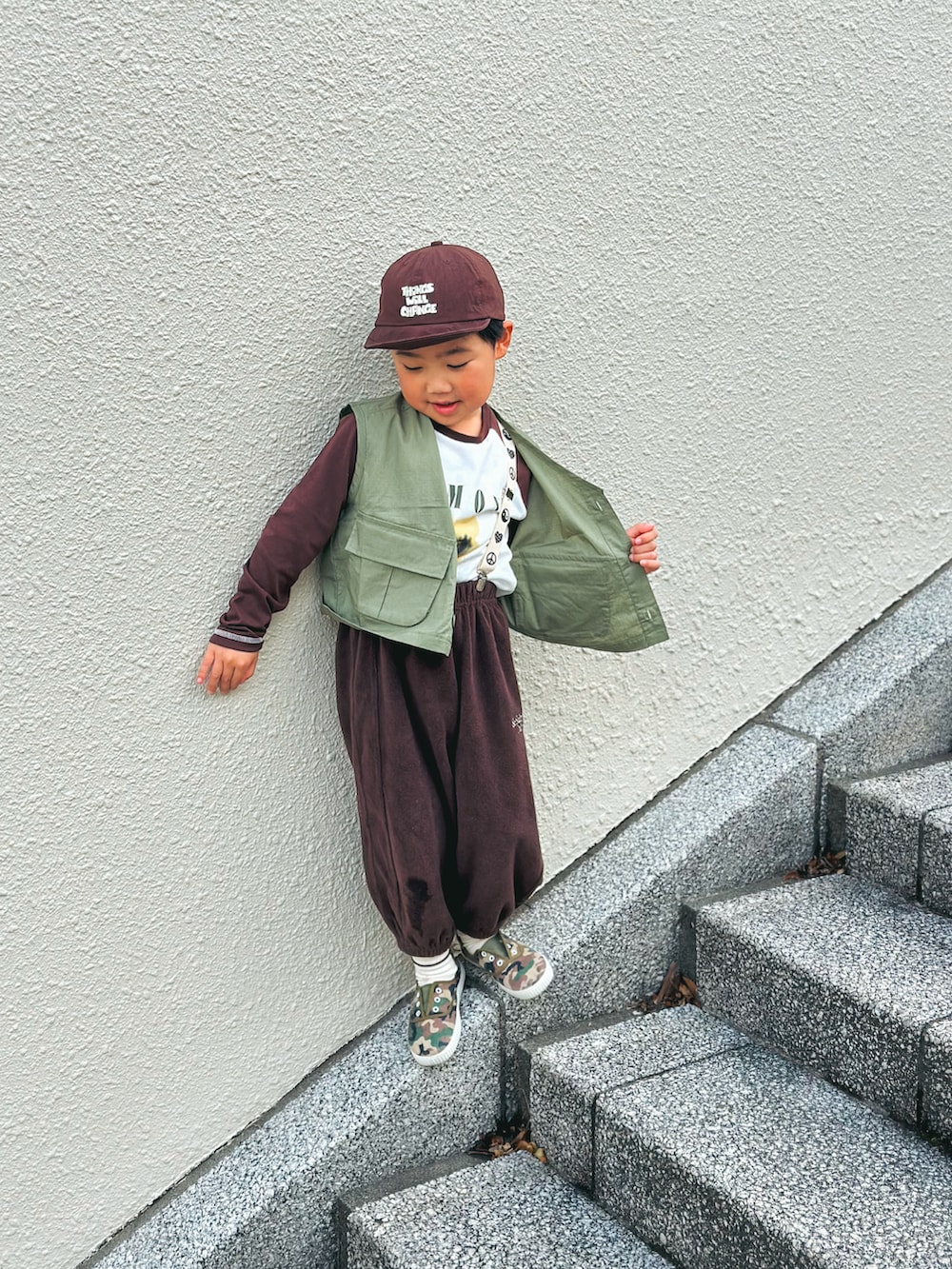 グリーン系のベスト、ブラウン系のTシャツ/カットソー、ブラウン系のスウェットパンツを着用したキッズの春コーディネートの2枚目の写真