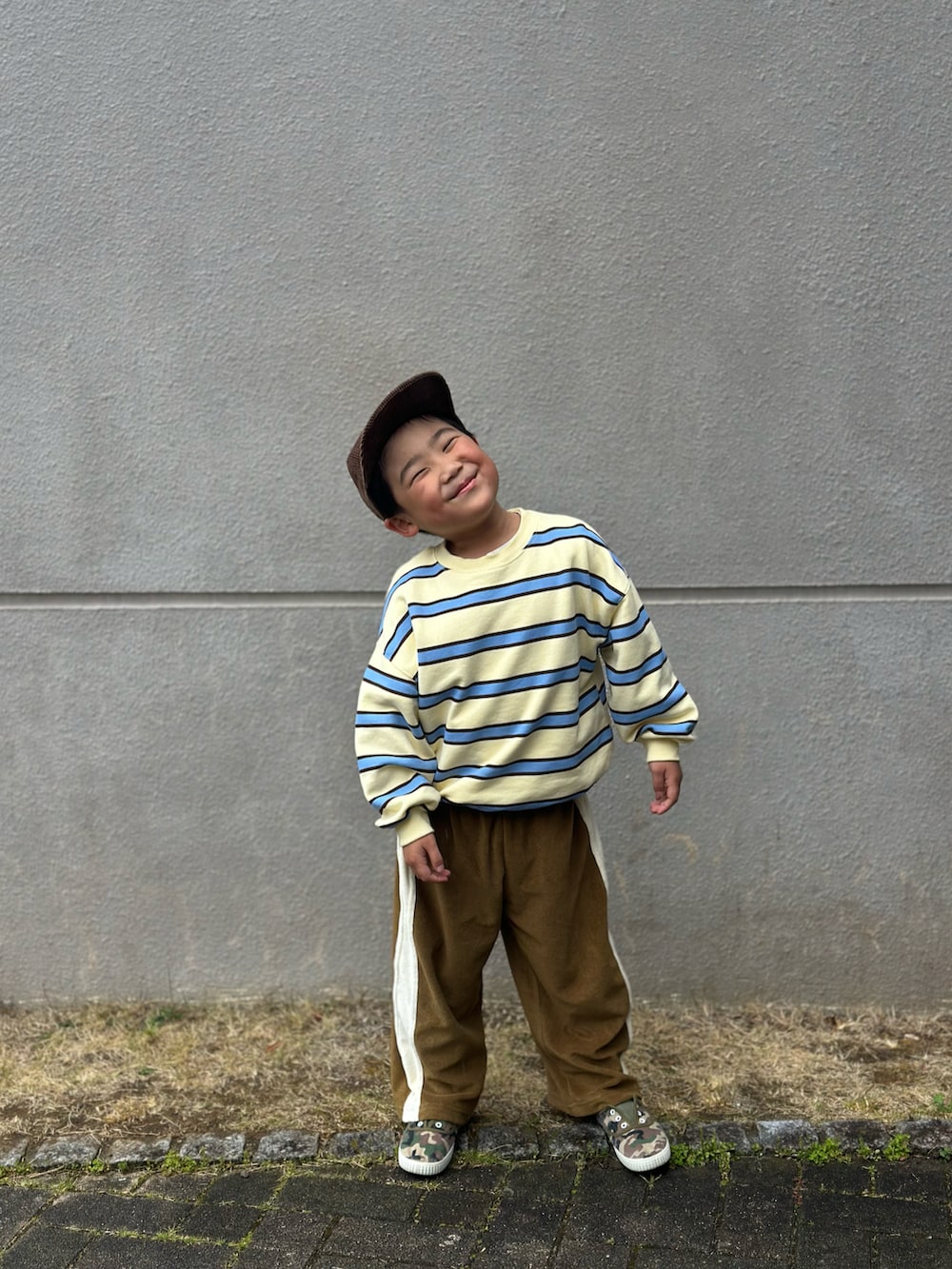 イエロー系のスウェット、ブラウン系のパンツ、グリーン系のシューズを着用したキッズの春コーディネートの2枚目の写真