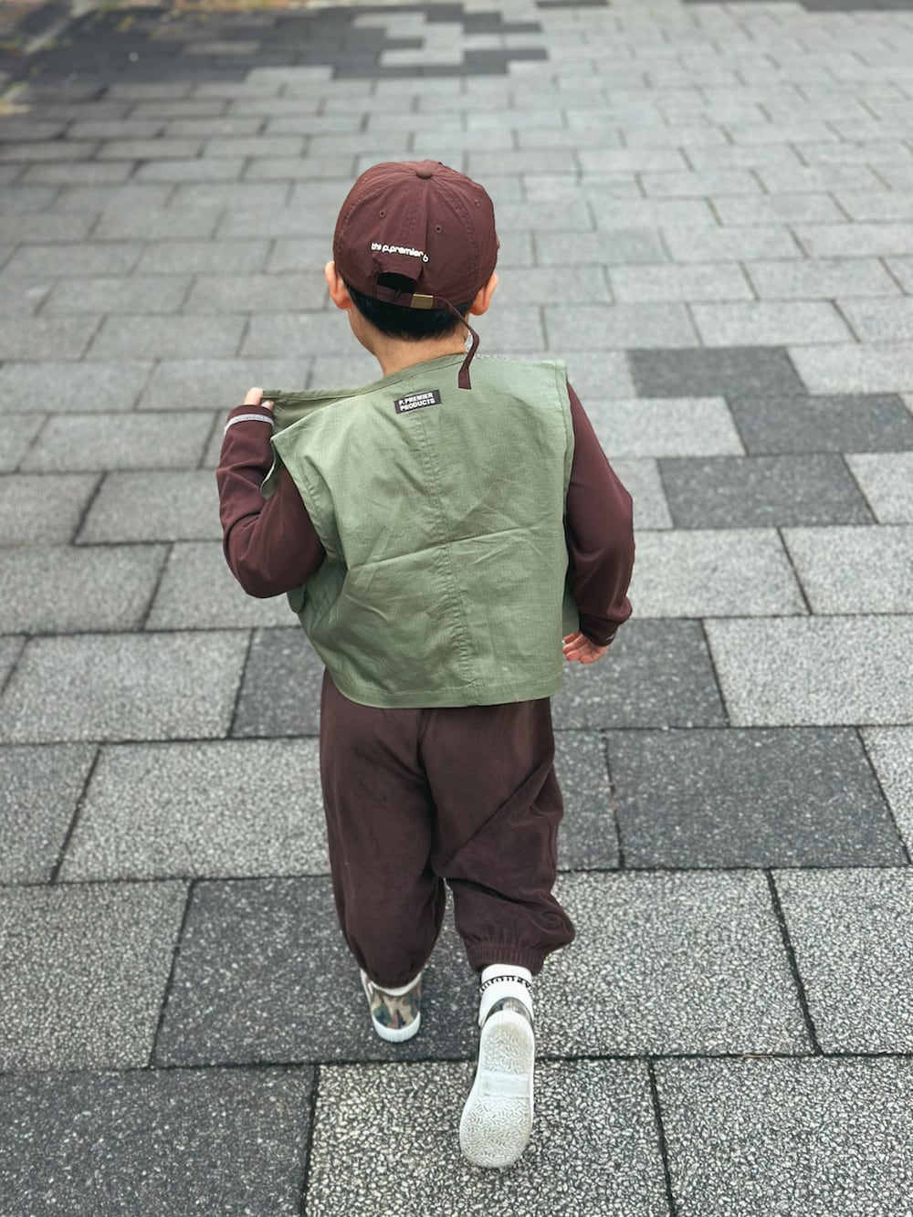 グリーン系のベスト、ブラウン系のTシャツ/カットソー、ブラウン系のスウェットパンツを着用したキッズの春コーディネートの3枚目の写真