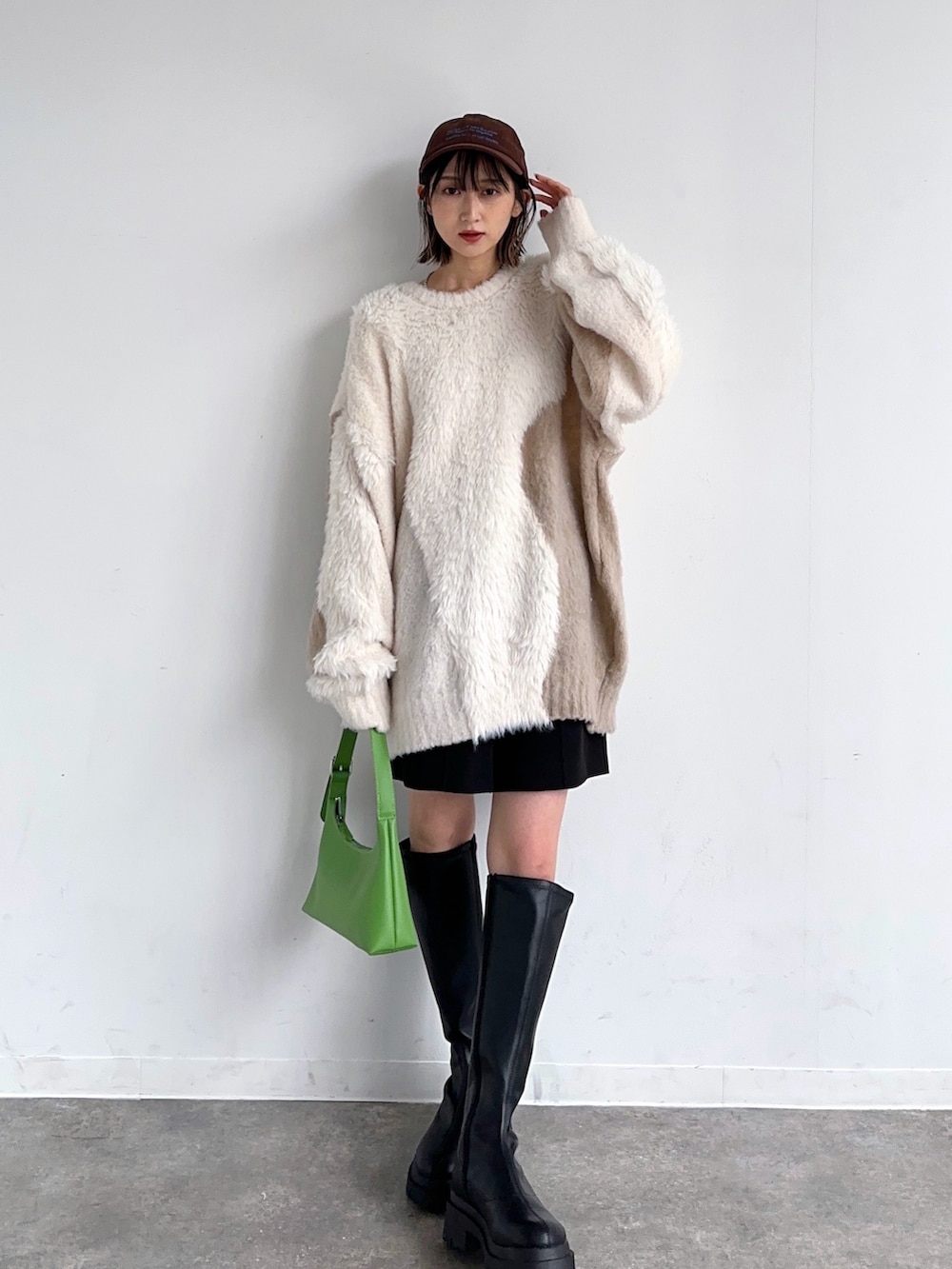 ベージュ系のカーディガン/ボレロ、グリーン系のハンドバッグ、ブラウン系のキャップを着用したレディースの秋コーディネートの2枚目の写真