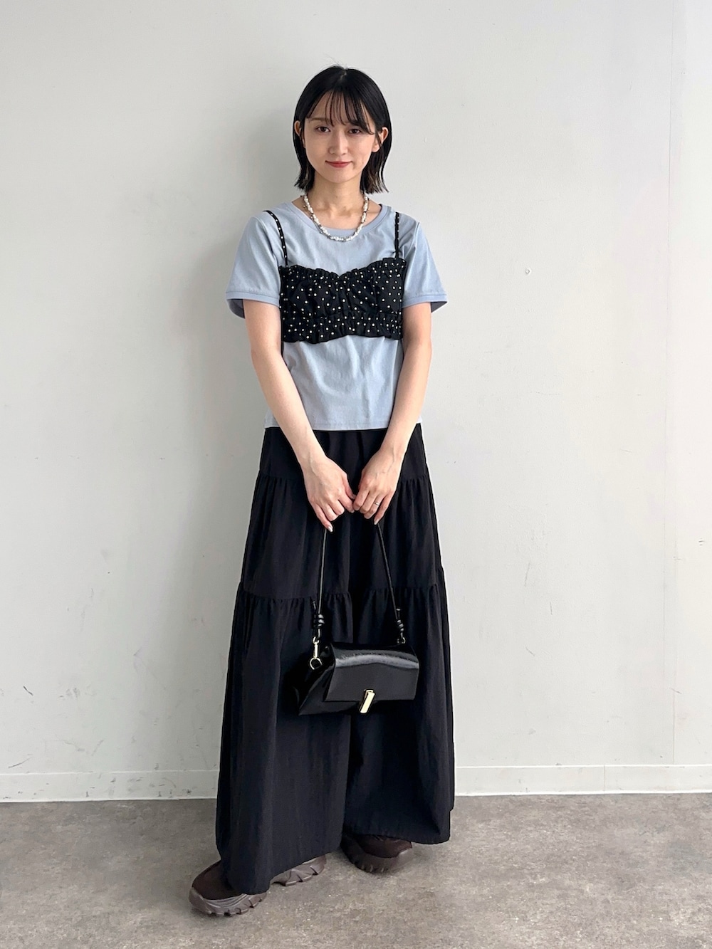 ブラック系のシャツ/ブラウス、ブラック系のスカート、ブラウン系のスニーカーを着用したレディースの春コーディネートの2枚目の写真