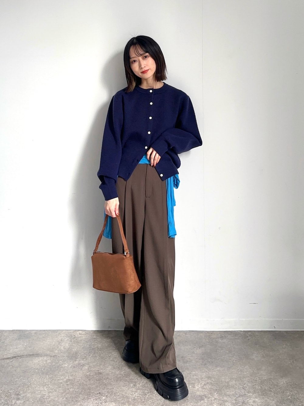 ブルー系のカーディガン/ボレロ、ブルー系のTシャツ/カットソー、ブラウン系のスラックスを着用したレディースの秋コーディネートの2枚目の写真