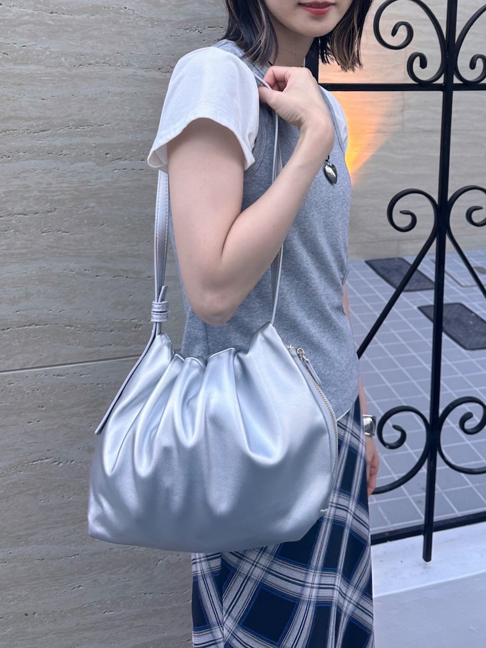 シルバー系のハンドバッグ、グレー系のTシャツ/カットソー、ブルー系のスカートを着用したレディースの夏コーディネートの2枚目の写真