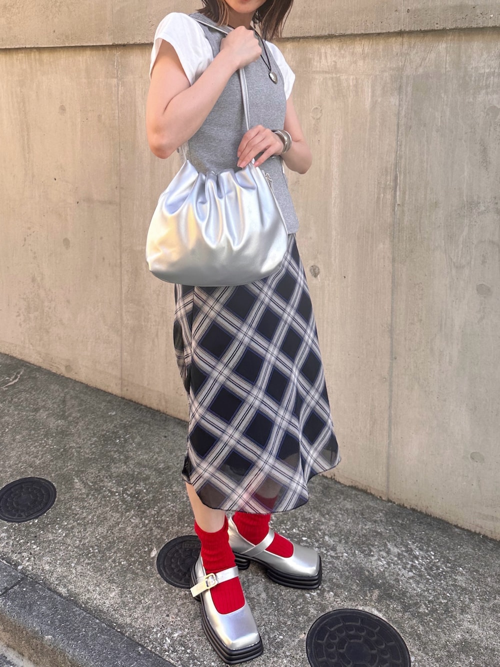 シルバー系のハンドバッグ、グレー系のTシャツ/カットソー、ブルー系のスカートを着用したレディースの夏コーディネートの4枚目の写真